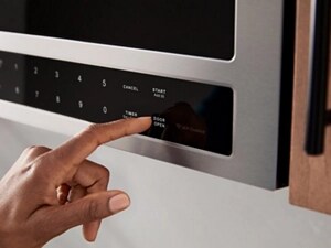 A person pushing a button on a microwave