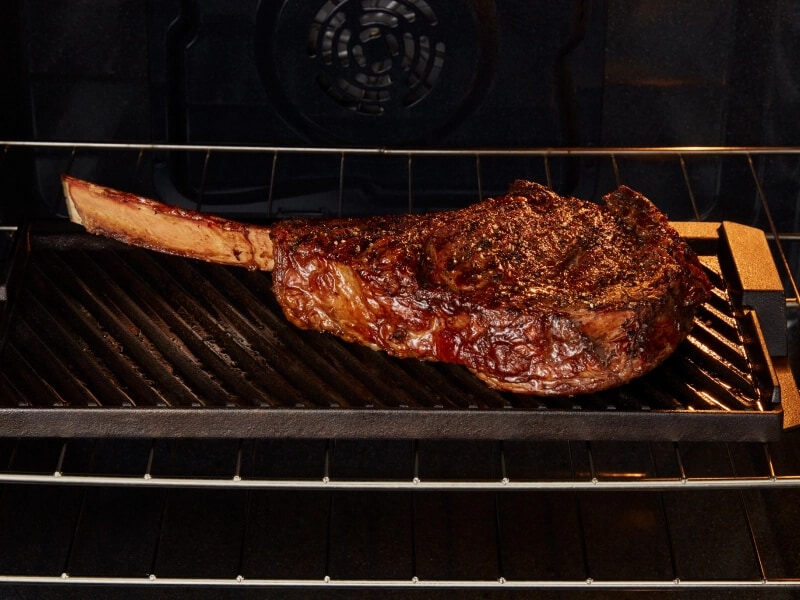 Grilling a steak inside a Maytag® range