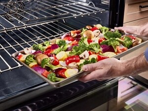 Person putting a sheet pan of veggies inside of a range
