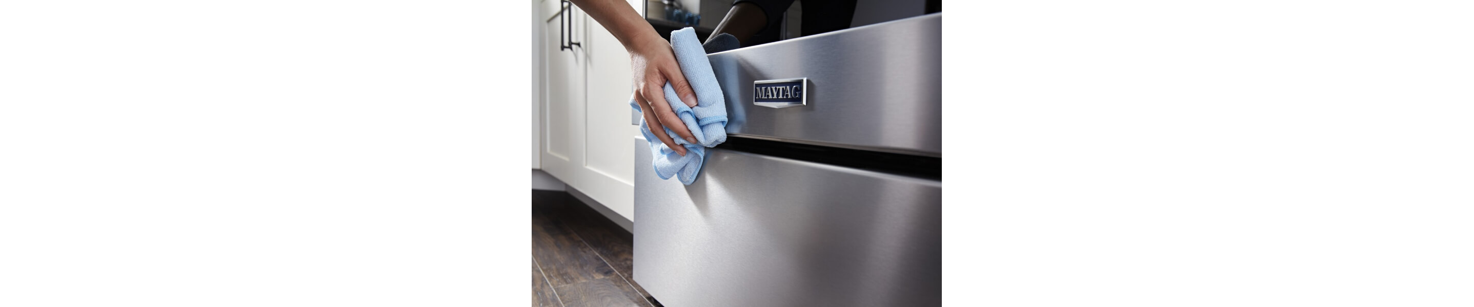 Person wiping the stainless steel of a Maytag® range