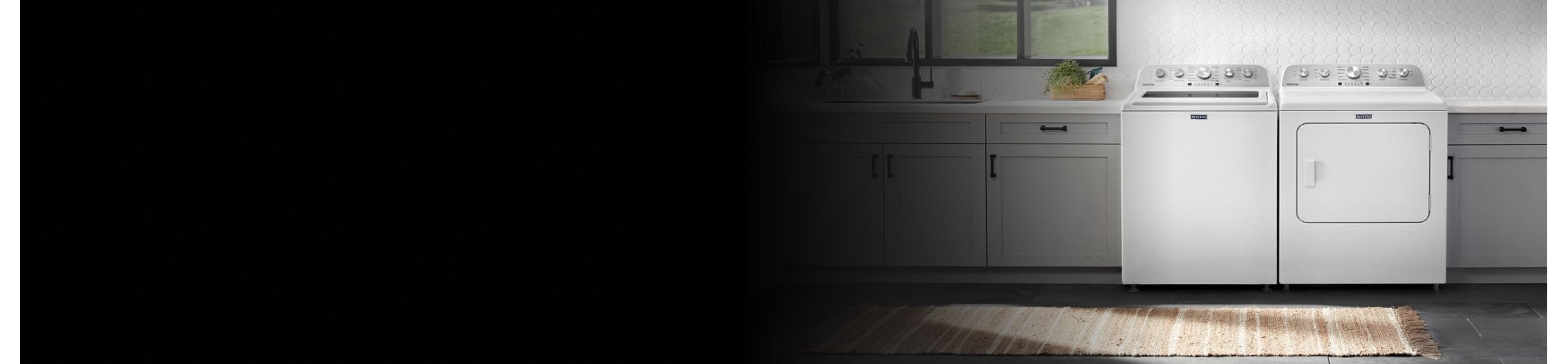 White front load laundry pair in between grey cabinets in a laundry room