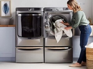 A woman loading a white towel into a Maytag® washer