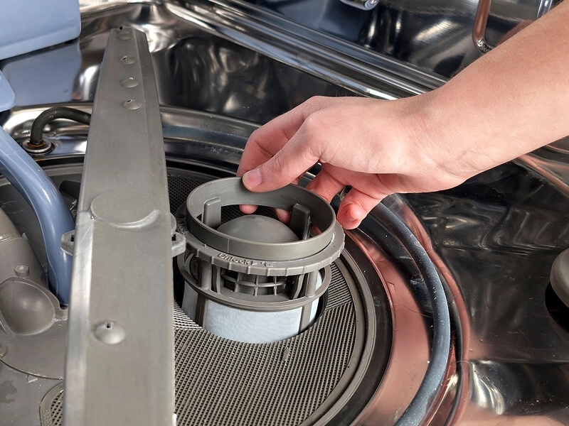 A person replacing a dishwasher filter