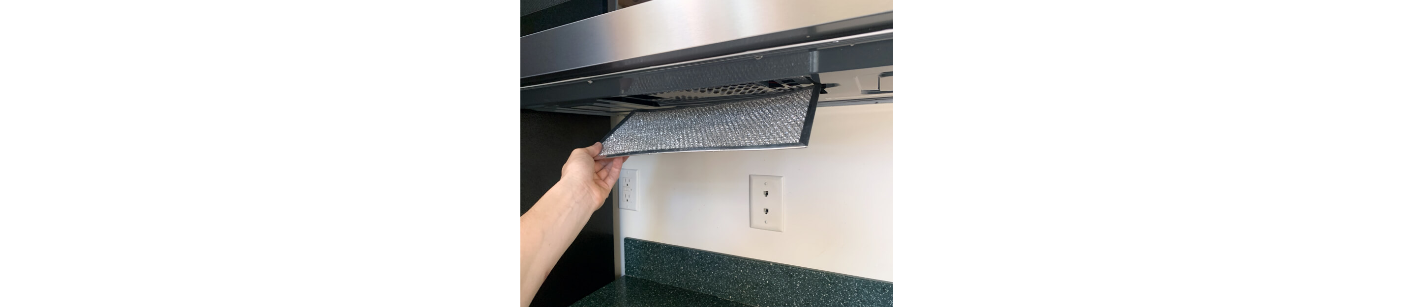 Hand removing grease filter from bottom of the microwave