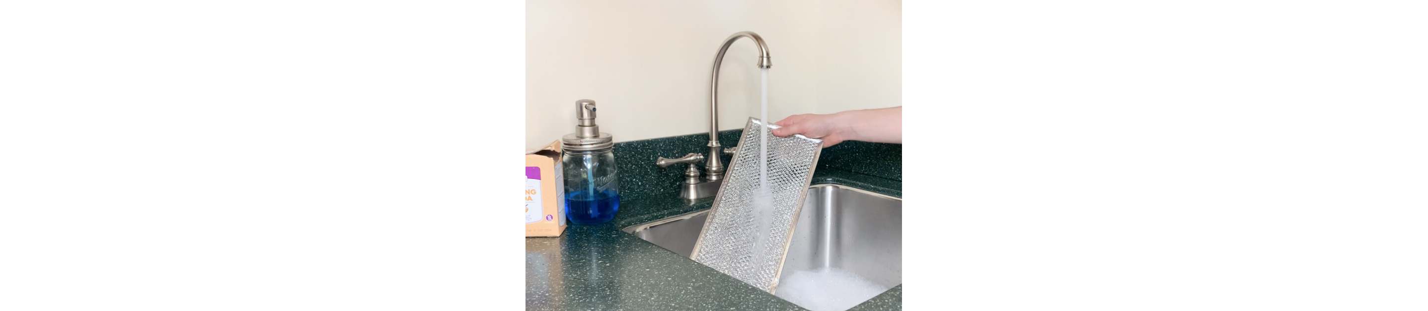 Grease filter being rinsed under a running faucet 