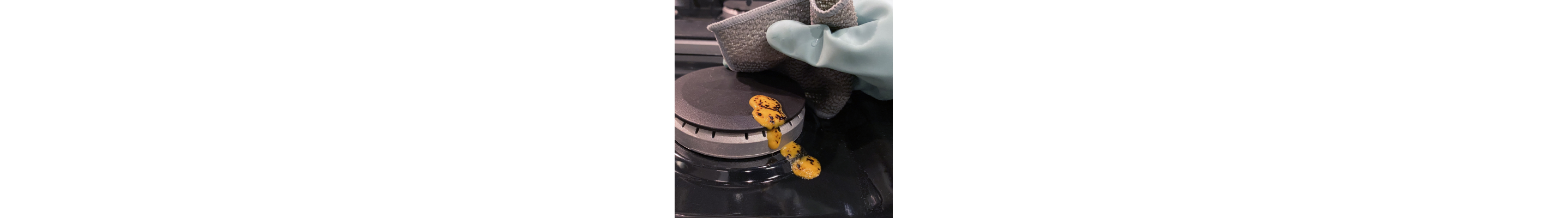 Hand wiping cheese off gas burner cap