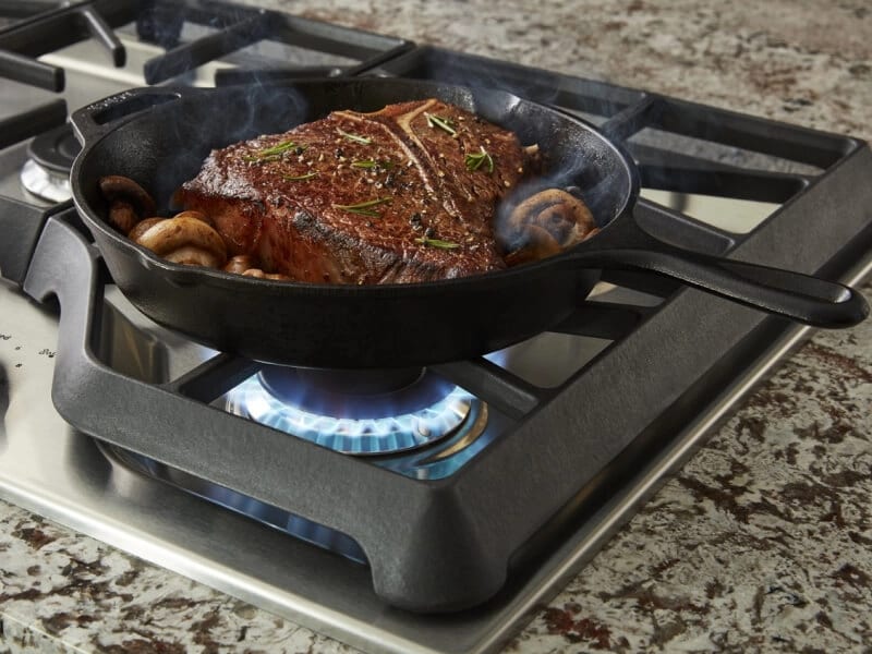 Steak cooking in a cast iron pan on the stove