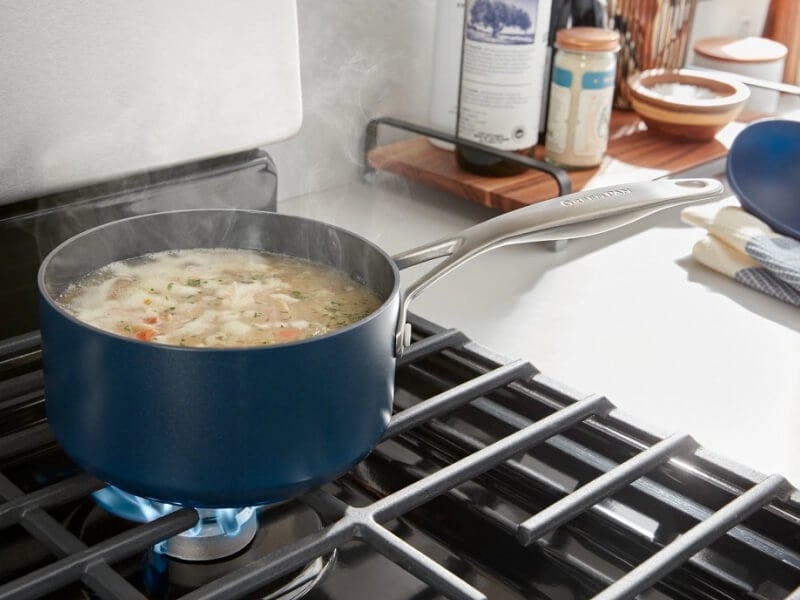 A blue pot of soup simmering on the stove