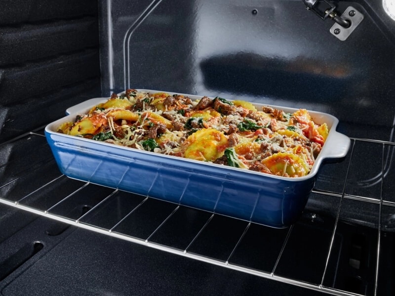 A blue ceramic dish in the oven baking casserole