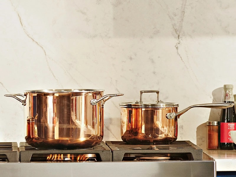 Two copper pots sitting on a stove