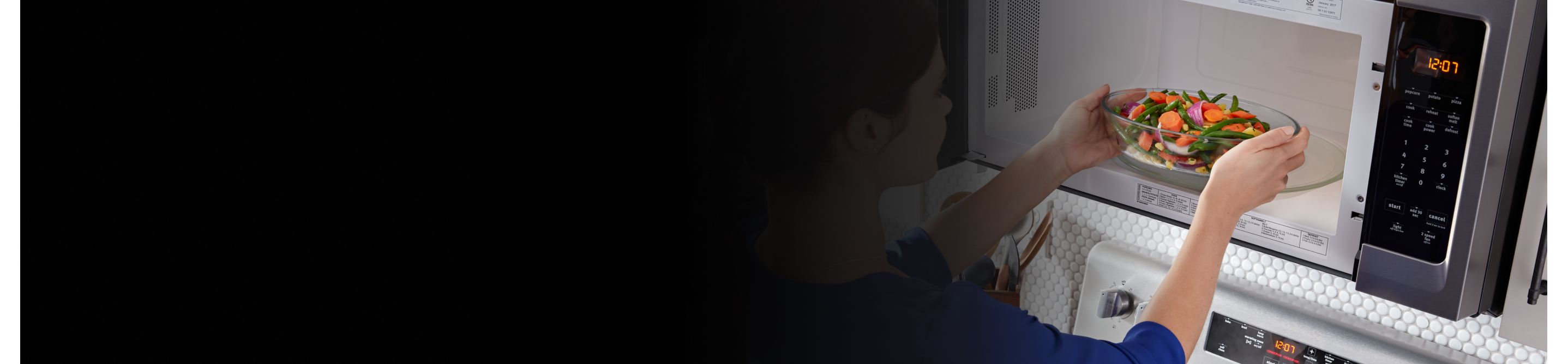 Person placing a bowl of vegetables inside a microwave