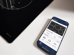 Phone next to a cooktop open to the Maytag® App