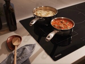 Food cooking in sauce pots on a cooktop