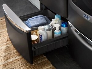 A Maytag® washer pedestal with laundry supplies
