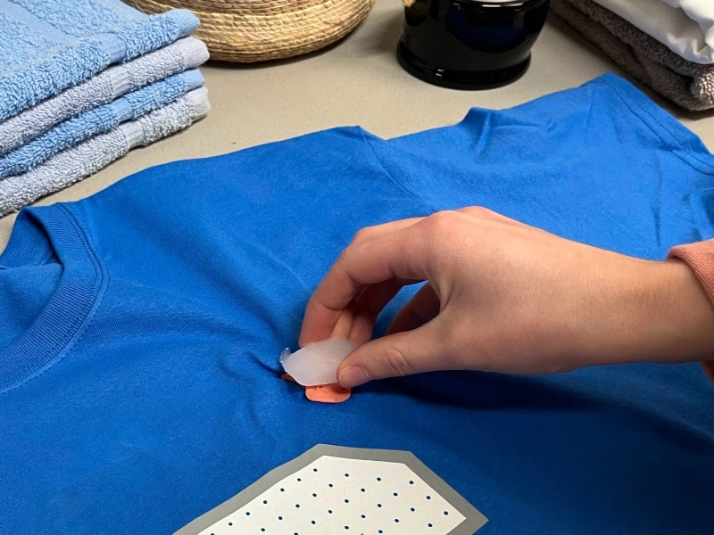 Person placing ice on gum stuck on a jersey