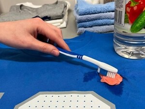 Person scrubbing gum with a toothbrush
