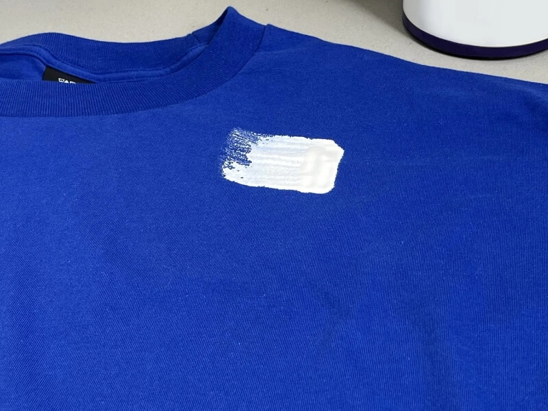 Paint on a blue shirt with cleaning supplies shown behind it