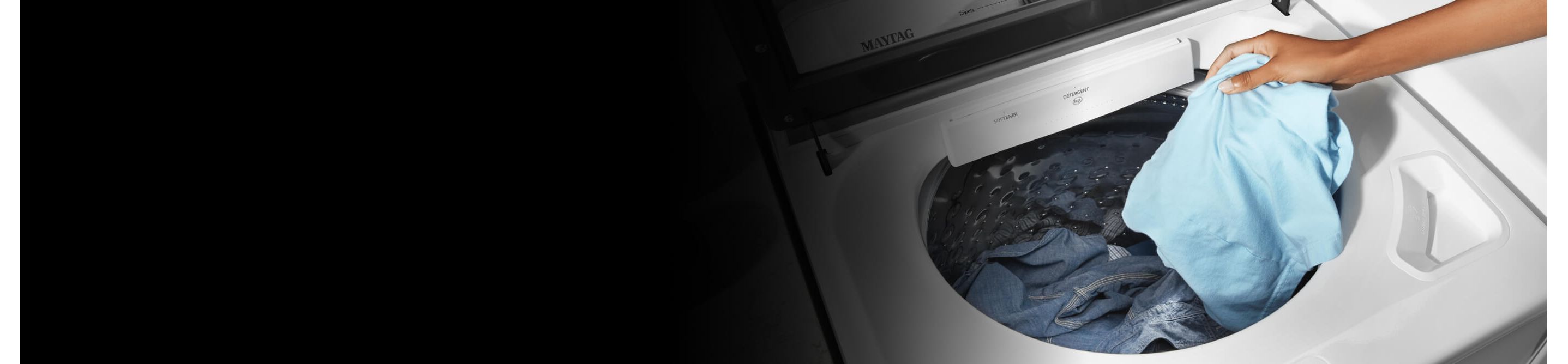Person putting a blue shirt into a washing machine