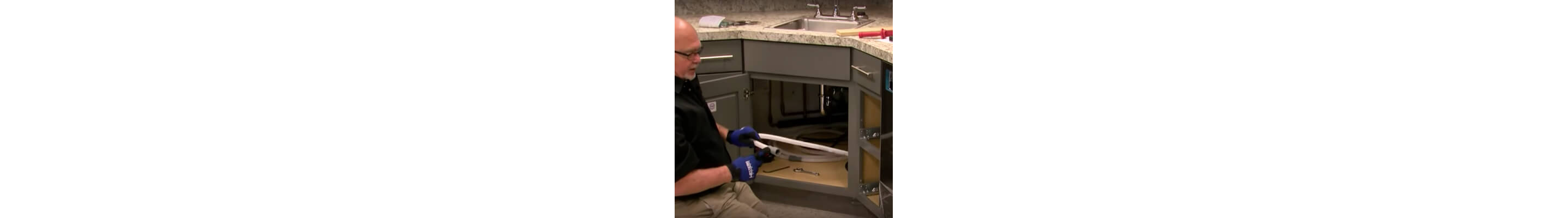 A person connecting dishwasher hoses