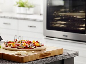 Uncooked pizza on a wooden cutting board
