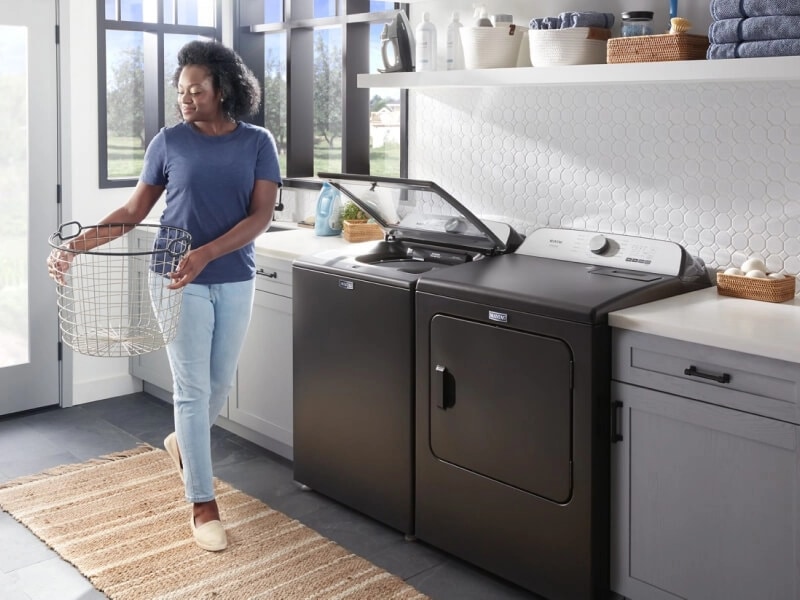 Person carrying a basket through their laundry room