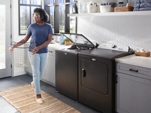 Person carrying a basket through their laundry room