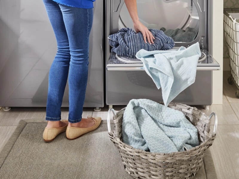 Person unloading their dryer into a basket on the floor