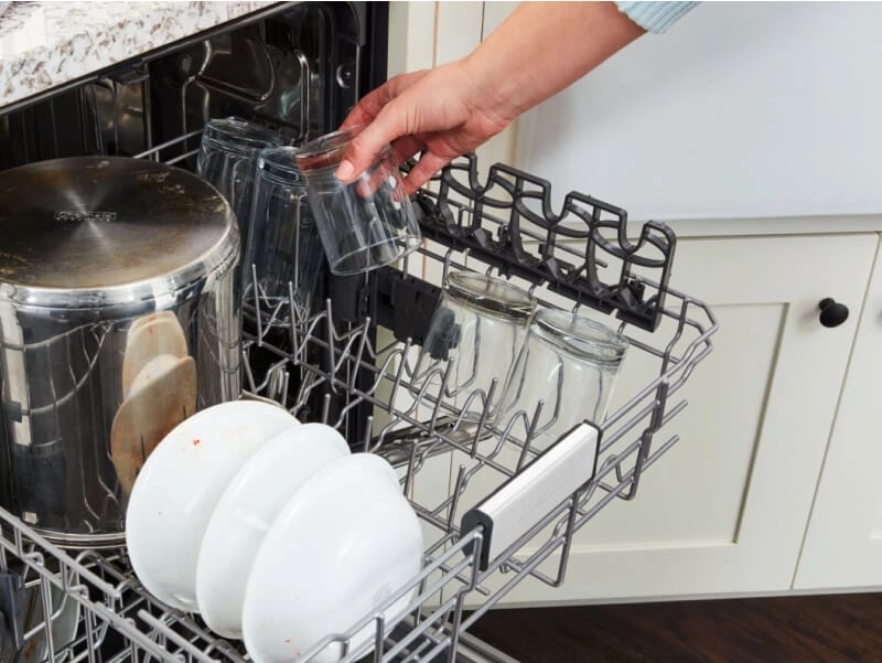 Person loading dishes into a dishwasher top rack