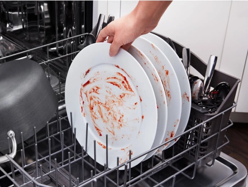 Person loading soiled dishes into a dishwasher