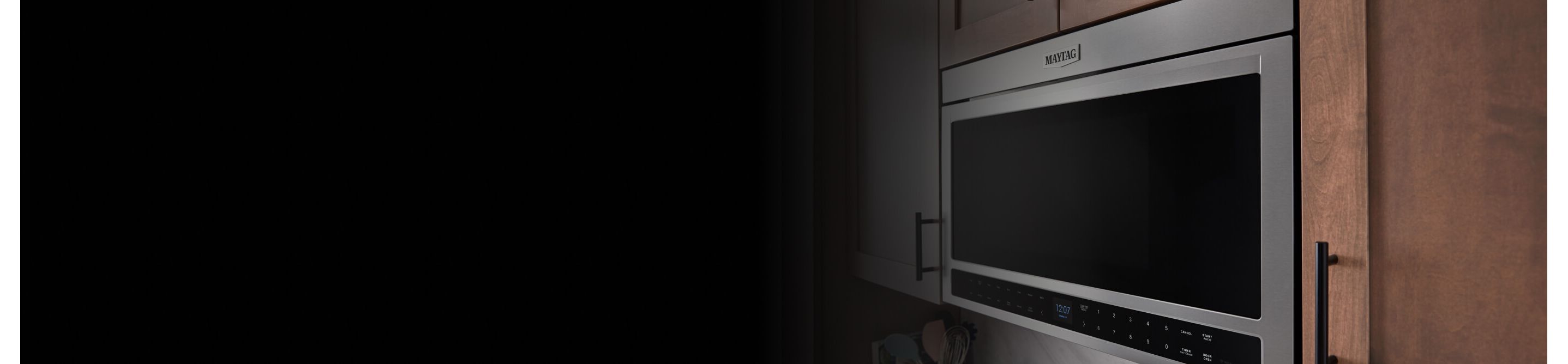 A Maytag® over-the-range built-in microwave surrounded by brown upper cabinets