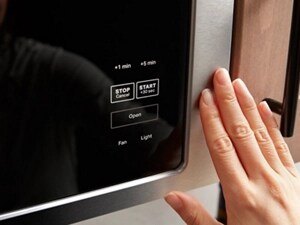 Fingers next to a built-in microwave control panel