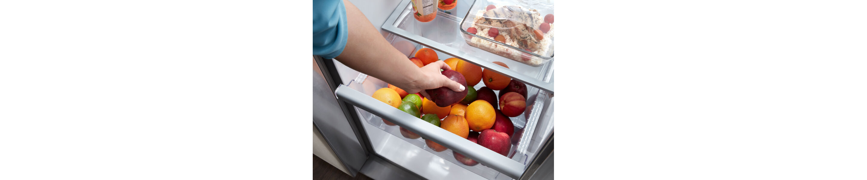A person storing apples in a fridge crisper drawer