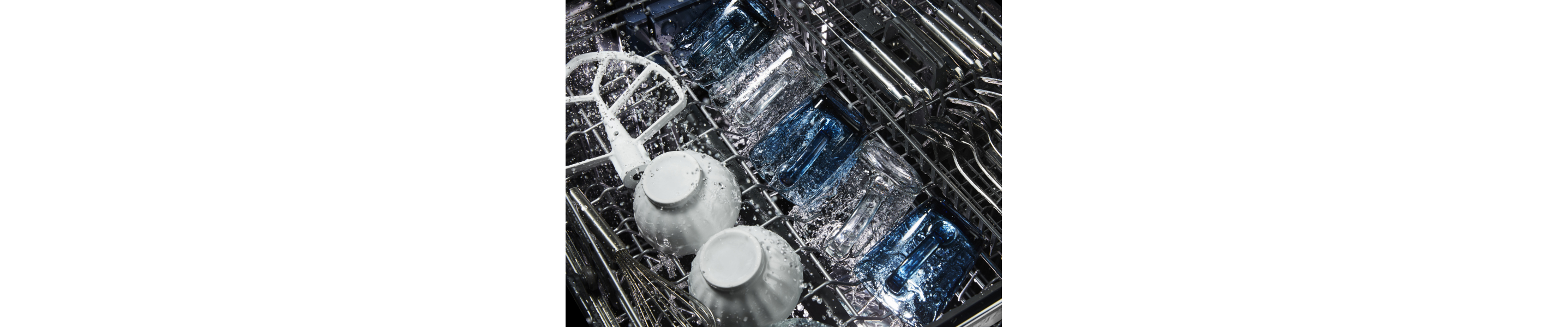 Glasses, bowls and silverware being cleaned in a dishwasher.