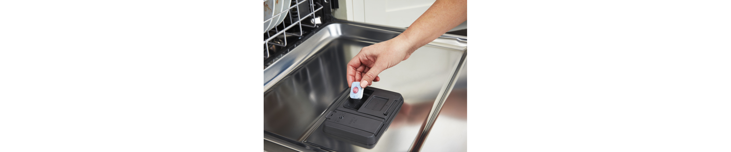 Person loading a detergent pack into a dishwasher.