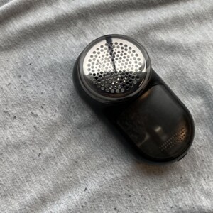 A fabric shaver on a pair of sweatpants with fabric pilling