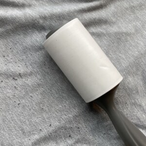 A lint roller on a pair of sweatpants with pilling