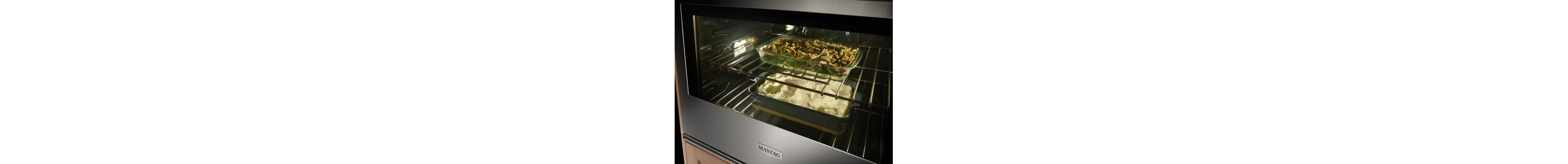 Pans of food cooking on racks of a Maytag® oven