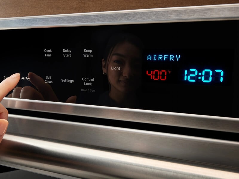 Reflection of woman setting her oven to the air fry setting