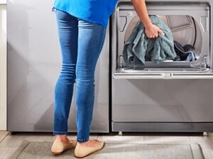 Person placing a teal towel inside of a white dryer