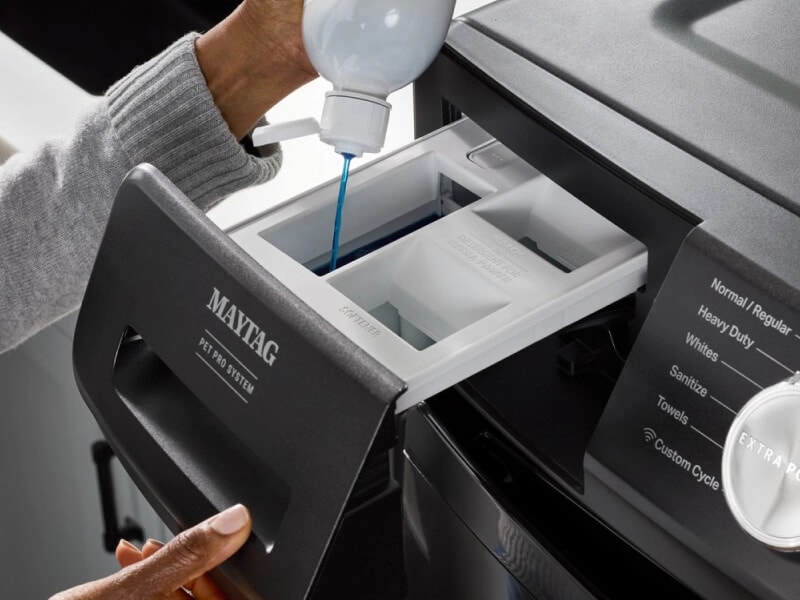 Person adding liquid laundry detergent to a Maytag® detergent dispenser
