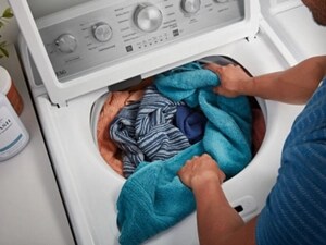 Person loading a washer with towels