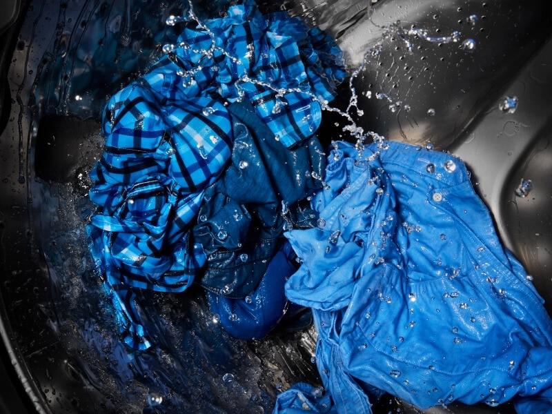 Wet blue clothes being washed in a washing machine