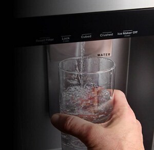 Person filling a glass with water from their refrigerator water filter