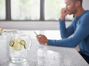 A person sitting at a kitchen counter with a pitcher of water in the foreground