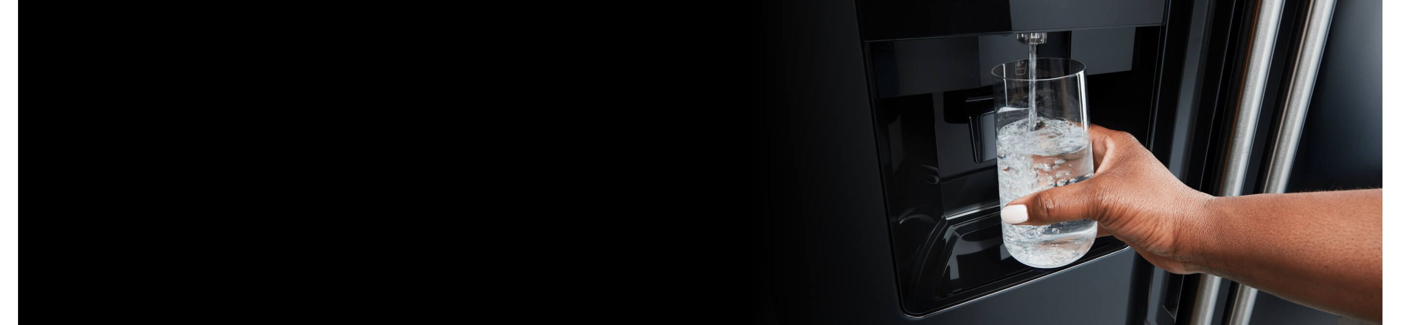 Person filling up their glass with water from a Maytag® refrigerator