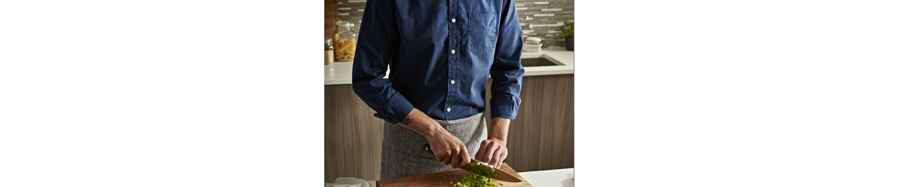 A man chopping broccoli on a cutting board in a modern kitchen with Maytag® appliances