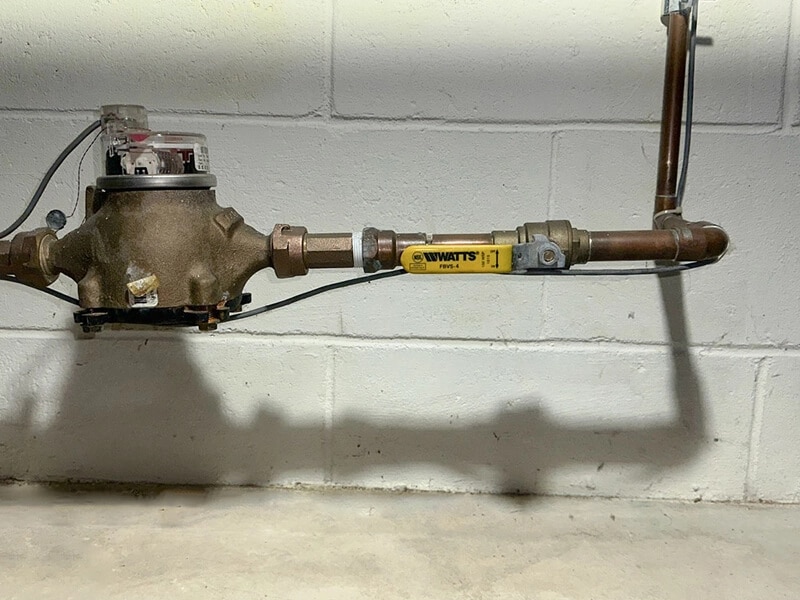 Water shut-off valve and pipes along cinderblock wall