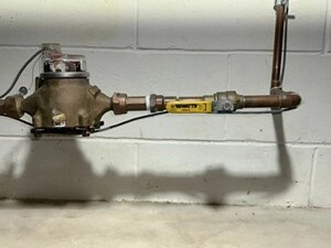 Water shut-off valve and pipes along cinderblock wall