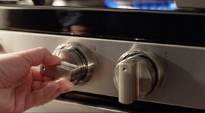Person adjusting burner heat on a gas stove