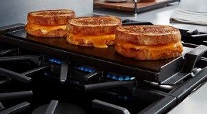 Grilled cheese browning on the griddle attachment of a gas stovetop 